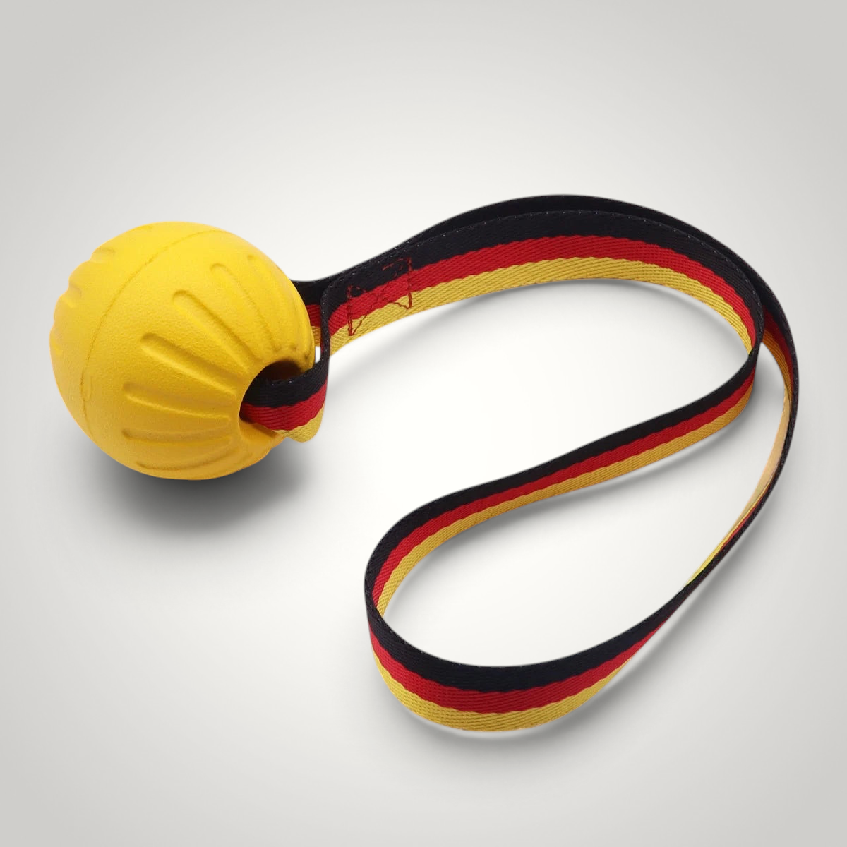 HappiFinds yellow EVA ball dog toy with a durable German flag patterned pull strap for tug and fetch play
