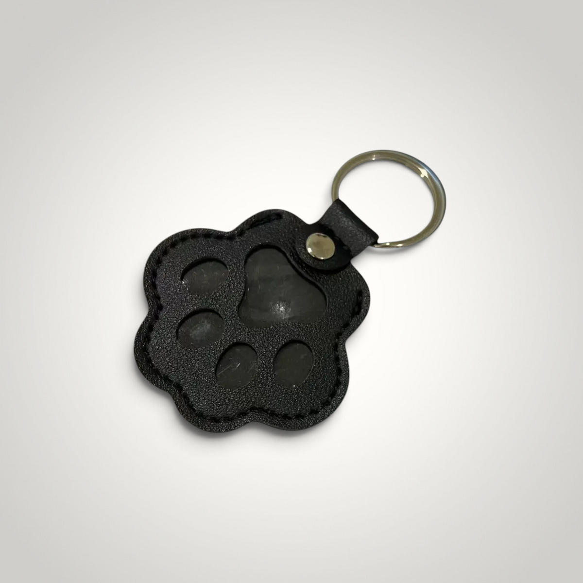 HappiFinds black faux leather paw-print dog hair collector keychain with a sturdy metal ring for easy attachment.