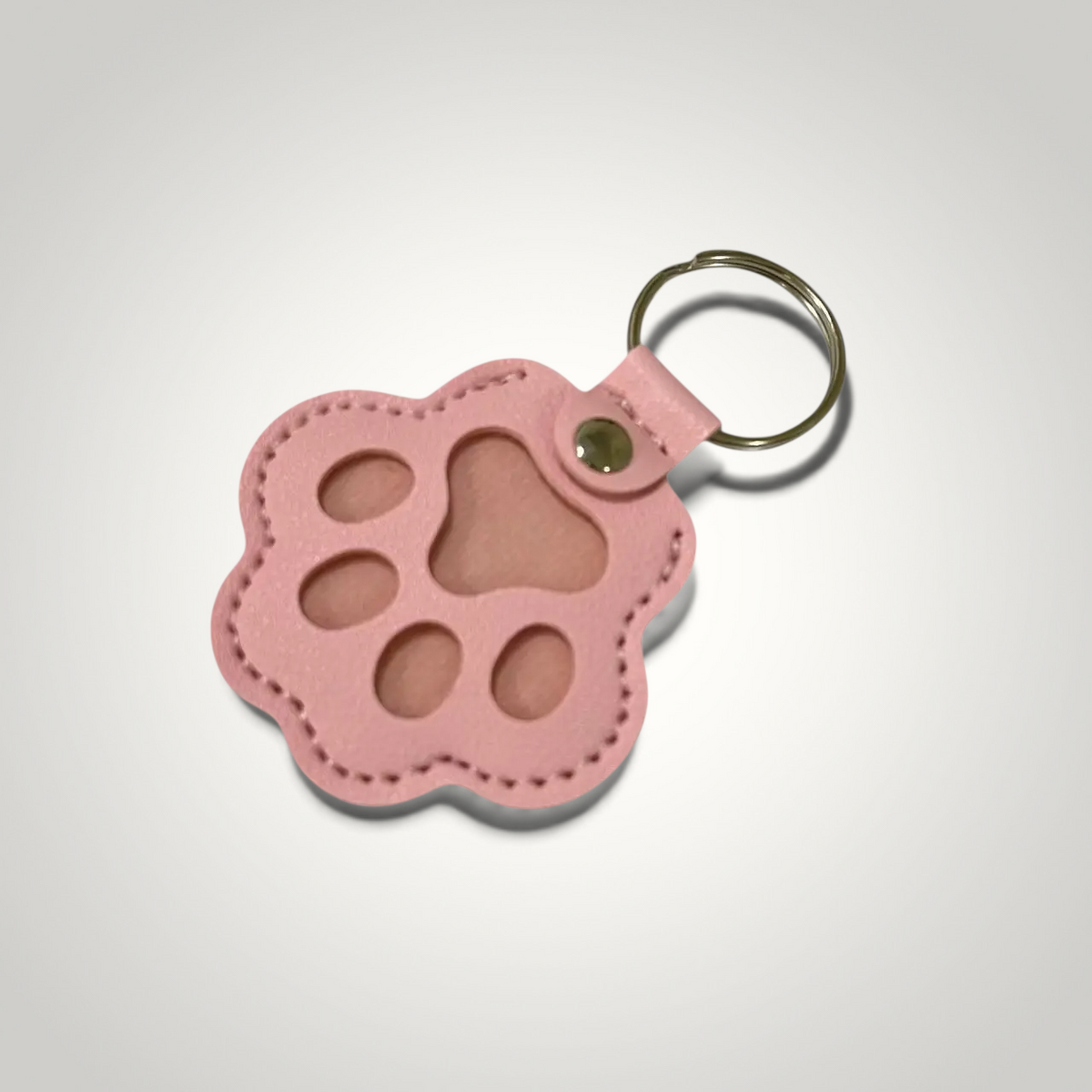 HappiFinds pink faux leather paw print keychain designed to collect pet hair from clothing and upholstery.