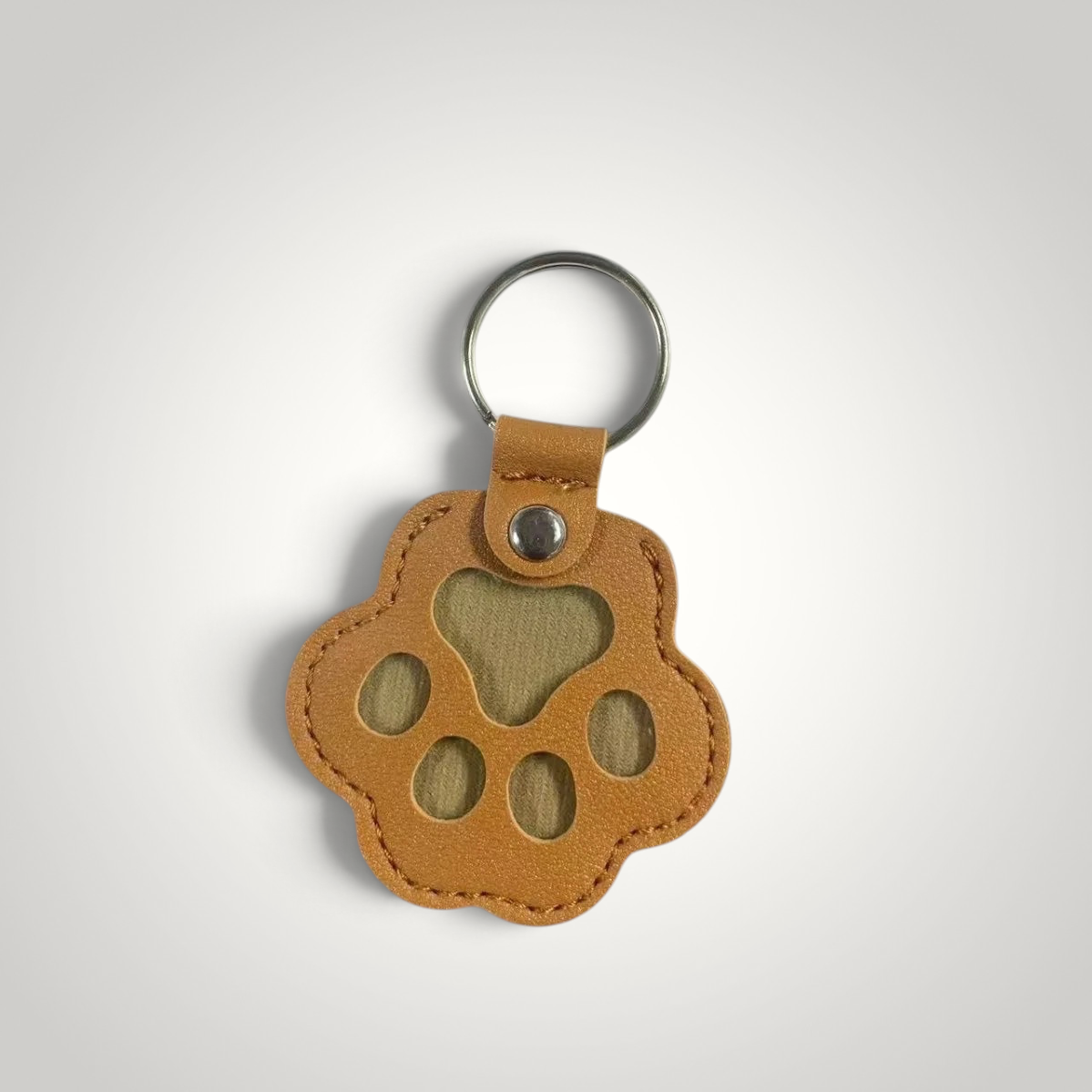 HappiFinds tan faux leather paw-print dog hair collector keychain with a metal ring for portable lint removal.