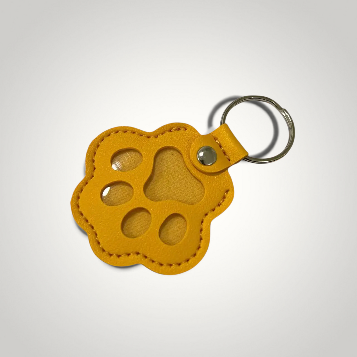 HappiFinds yellow faux leather paw-print dog hair collector keychain with a metal ring for easy attachment.